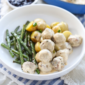 Swedish Meatballs on a plate with potatoes and green beans.