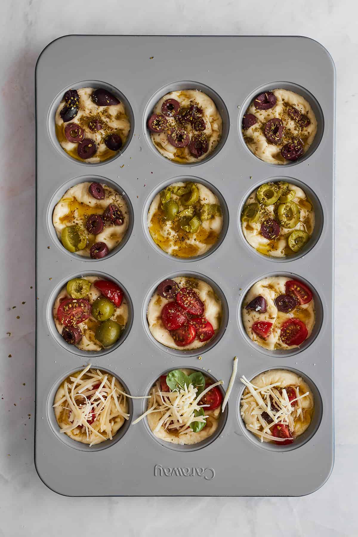 Rohbrot-Focaccia-Muffins mit Oliven, Tomaten und Käse in einer Muffinform. 
