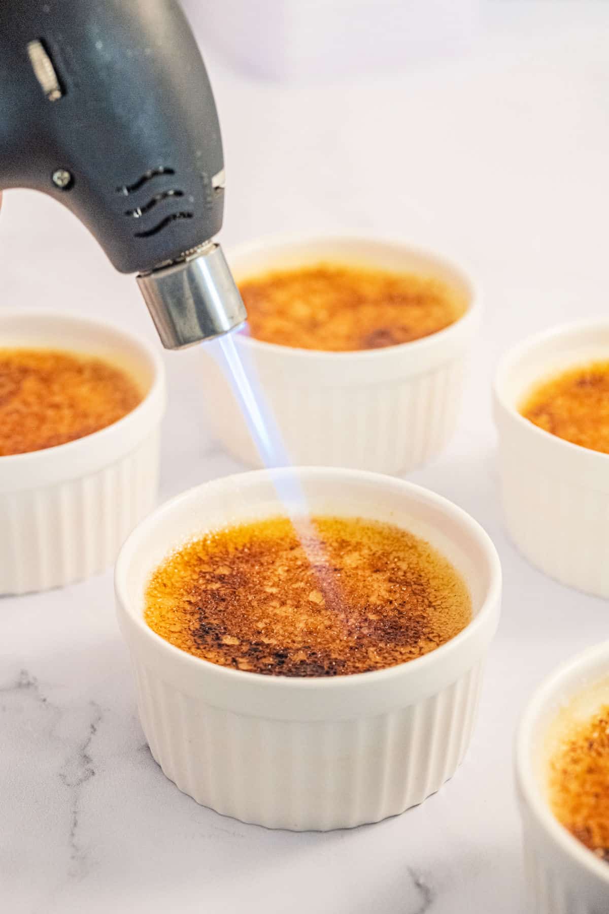 Zucker auf Crème Brûlée erhitzen.