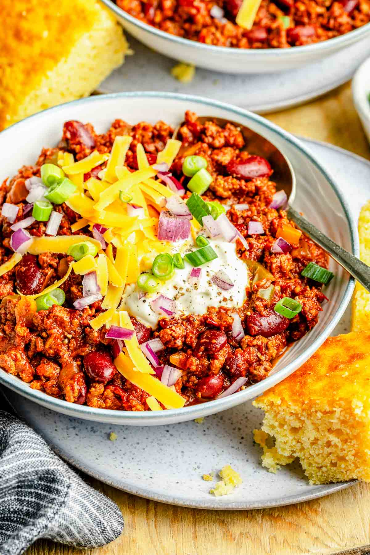 A bowl of slow cooker chili loaded with toppings.