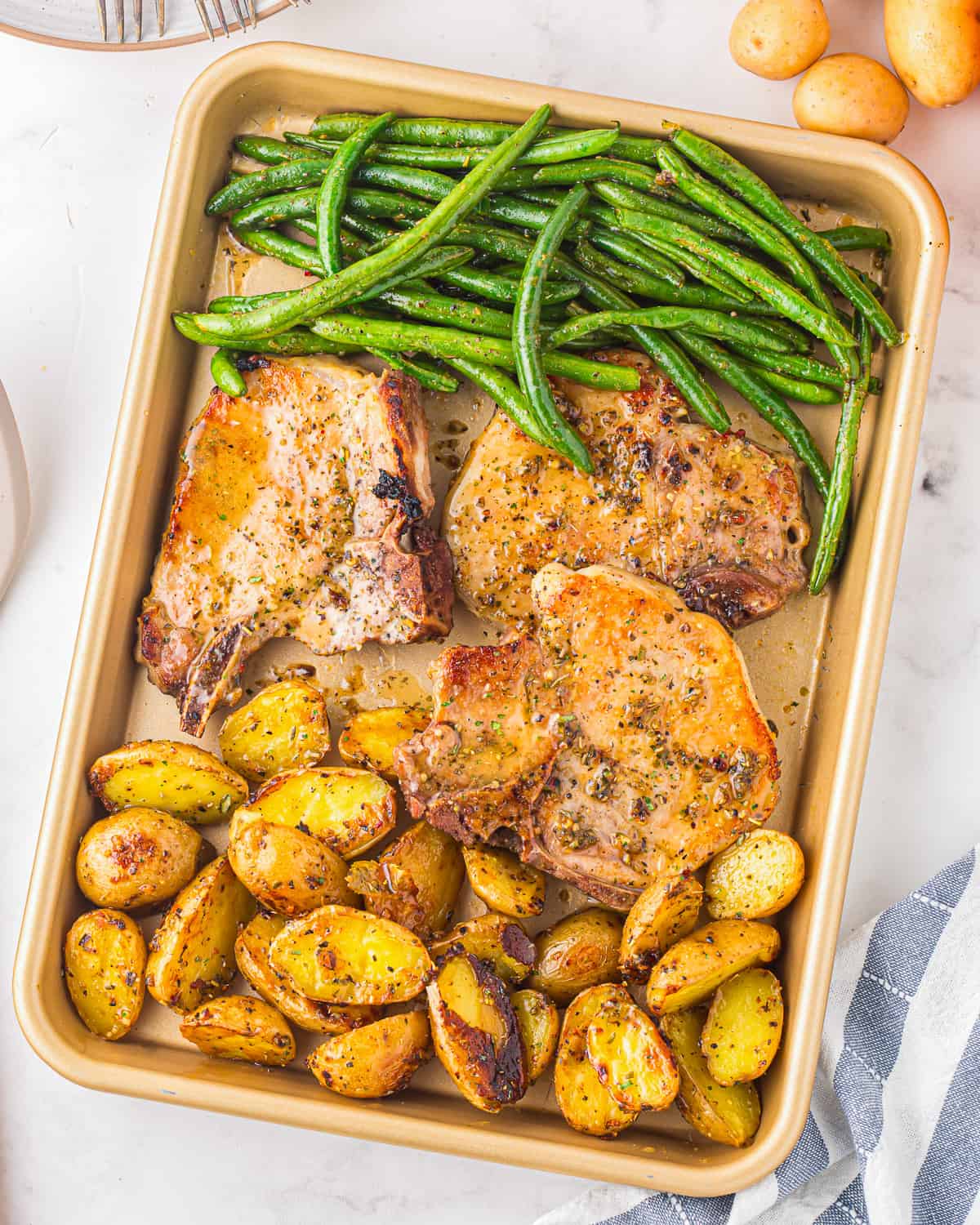 A baking sheet with potatoes and green beans.