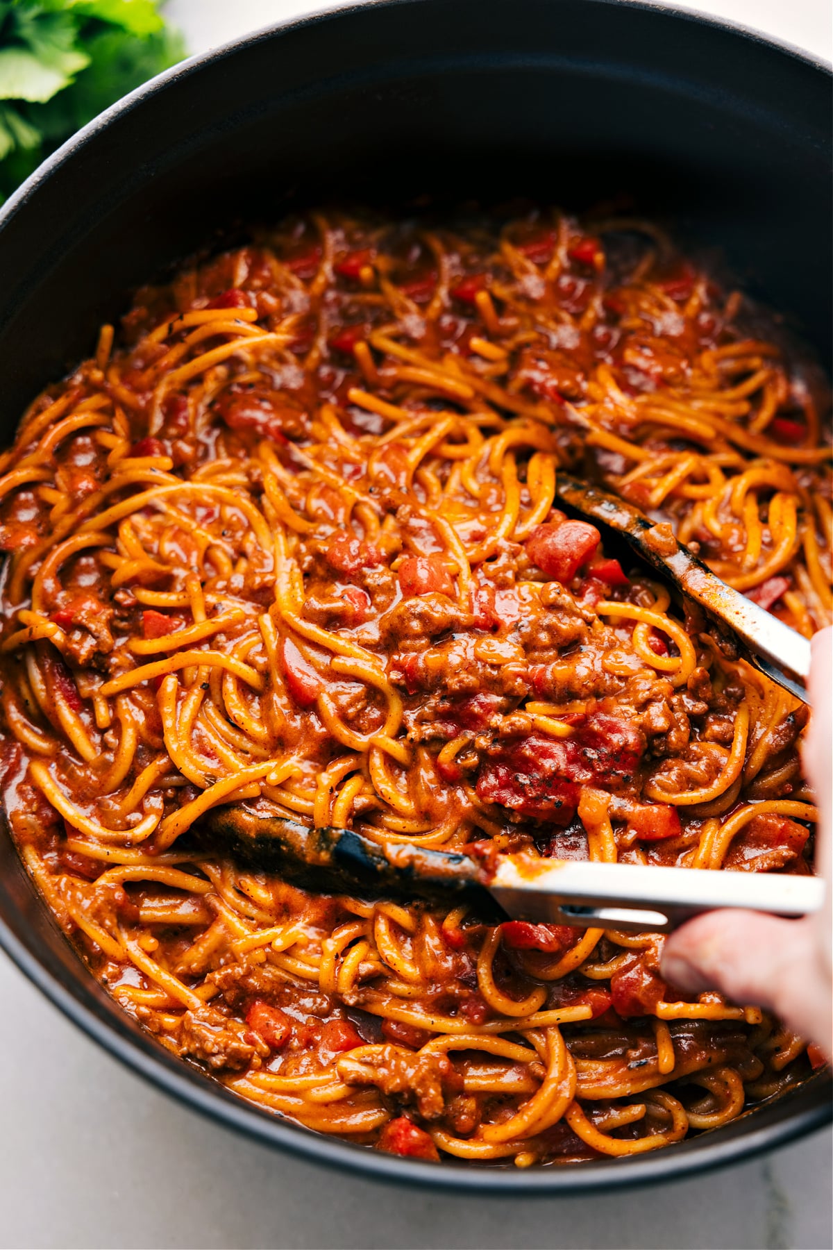 The best Taco Spaghetti in a pot with tongs about to scoop some up.